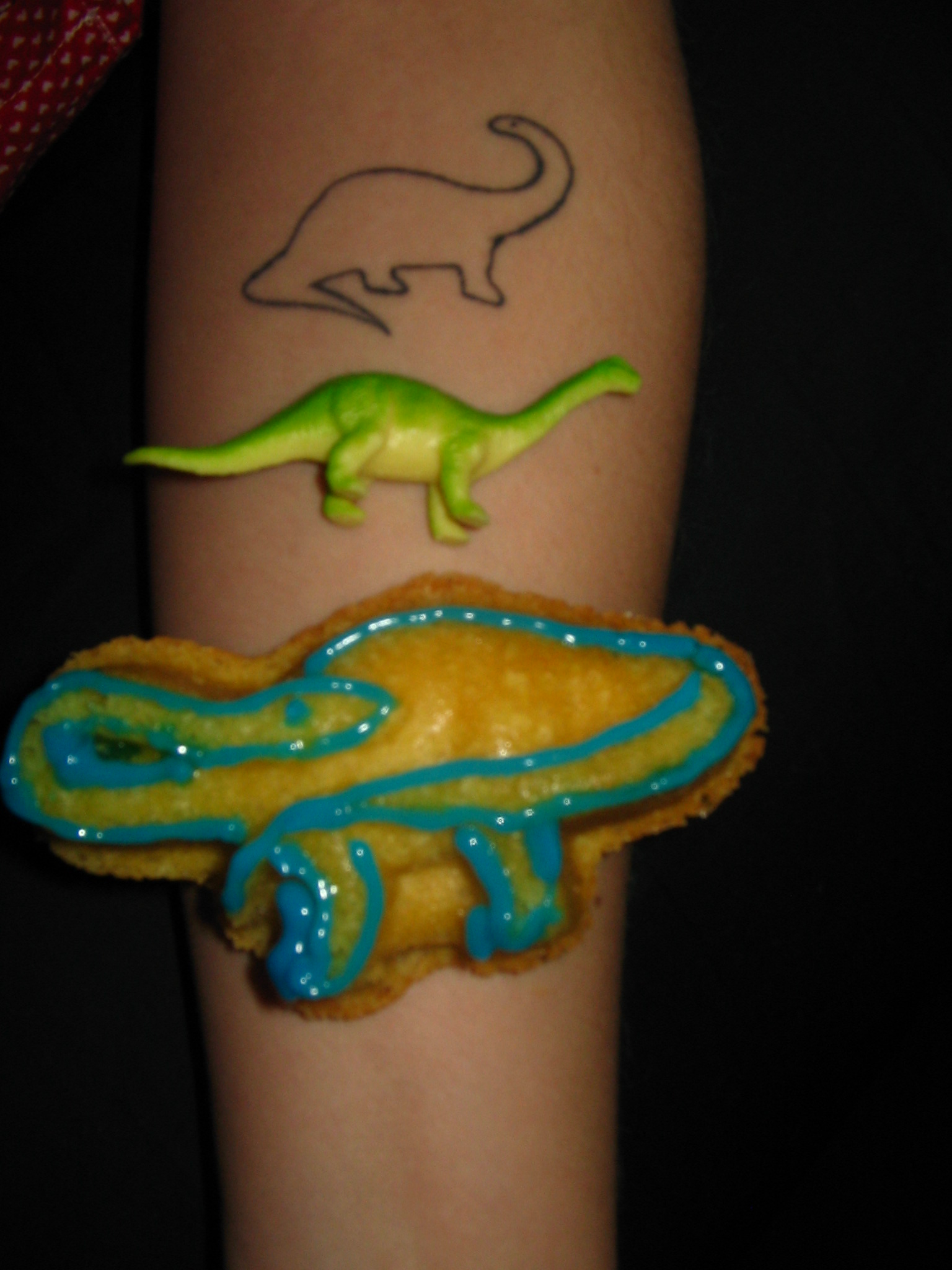 From top to bottom: Stella the Brontosaurus tattoo, a mini Brontosaurus figurine, and a Brontosaurus Vanilla Cupcake.